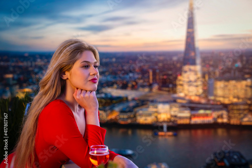 Photography A attractive, blonde woman in a red dress enjoys the elevated view over the illu