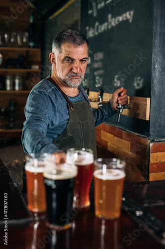 barman standing in bar. He is serving craft beer