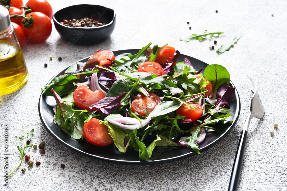 Mix salad with tomatoes, onions and olive oil in a black plate. Detox menu. The keto diet. Mix salad with tomatoes, onions and olive oil in a black plate. Detox menu. The keto diet.