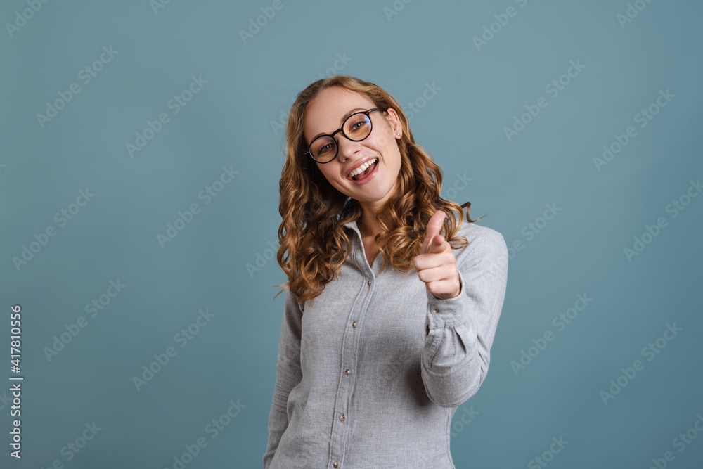 Happy girl in eyeglasses smiling and pointing finer at camera Happy girl in eyeglasses smiling and pointing finer at camera