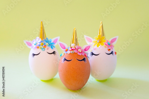 brown and white Easter eggs decorated in the form of unicorns on a green and yellow background, a minimal creative concept of a happy Easter