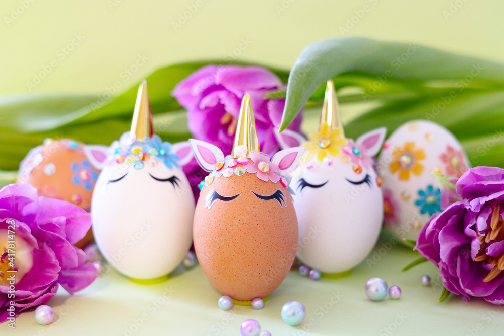 brown and white Easter eggs decorated in the form of unicorns on a green and yellow background with bouquet of tulips, a minimal creative concept of a happy Easter