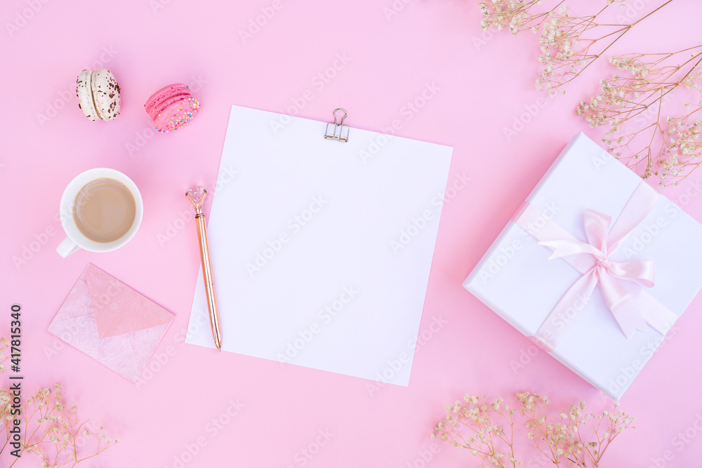 Notebook, cup of coffee and colorful macaron on pastel pink desk top view. Cozy morning breakfast. Fashion flat lay. Sweet macaroons.