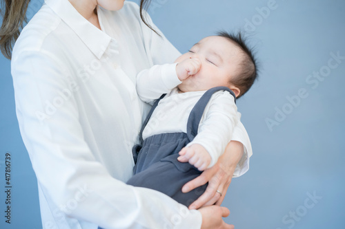 寝ている赤ちゃんを抱っこするお母さん