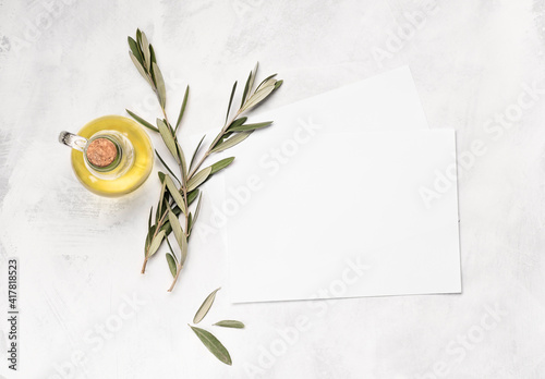 Minimalistic kitchen mock up  for invitation with paper for food recipes, olive branch and olive oil on the white background. Flat lay, top view