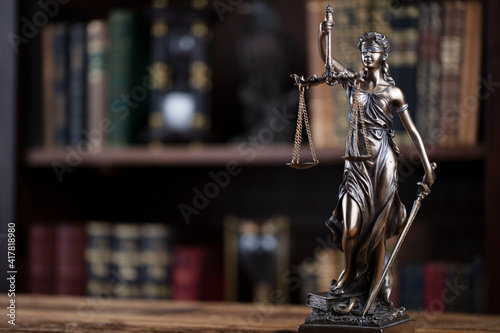 Law concept. Lawyer office. Themis statue on the shelf with legal books background. 