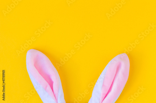 Plush rabbit ears on yellow background. Minimalist Happy Easter concept. Free space to design.