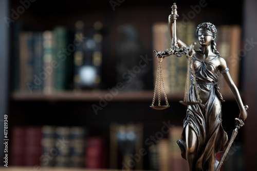 Law concept. Lawyer office. Themis statue on the shelf with legal books background. 