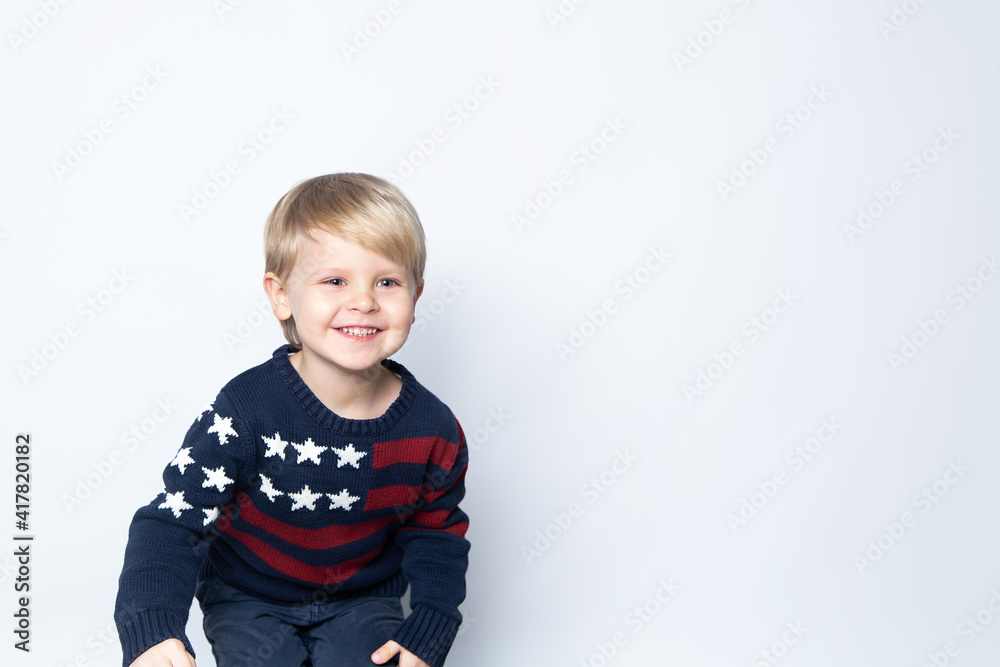 Happy boy in sweater with USA American flag on white background with copy space Happy boy in sweater with USA American flag on white background with copy space