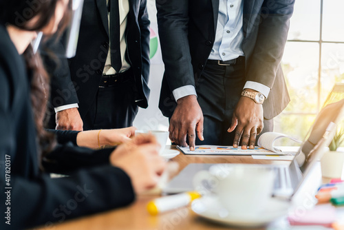 Close-up hands of African businessman planning and discuss with Caucasian colleagues that looking on documents at an internal business group meeting. Diversity of business people.