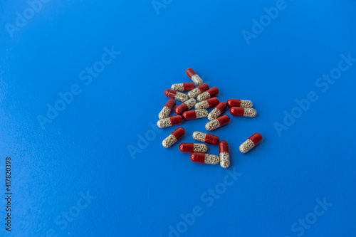 Various tablets and capsules, syringe, protective masks, on a blue background
