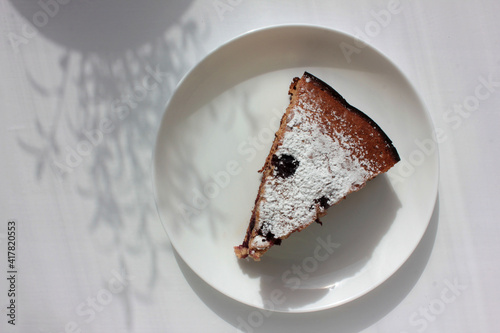 Pice of freshly baked cherry cake on white table background. Overhead view of homemade berry pie. Hard light, plant shadows