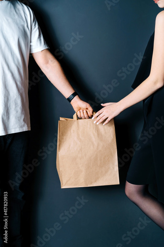 Disposable bag of kraft paper. Food delivery, hand-to-hand package transfer. The guy passes the package to the girl.