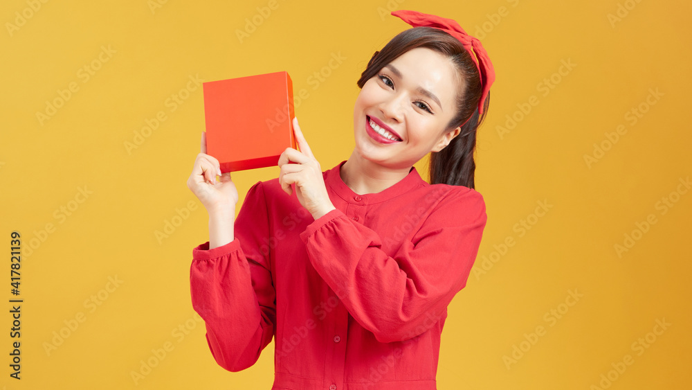 Young woman happy smile hold gift box in hands, isolated over yellow background Young woman happy smile hold gift box in hands, isolated over yellow background