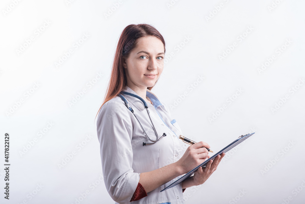 Portrait of a young female doctor in a white uniform with a folder and a pen in hands in the studio on a white background Portrait of a young female doctor in a white uniform with a folder and a pen in hands in the studio on a white background