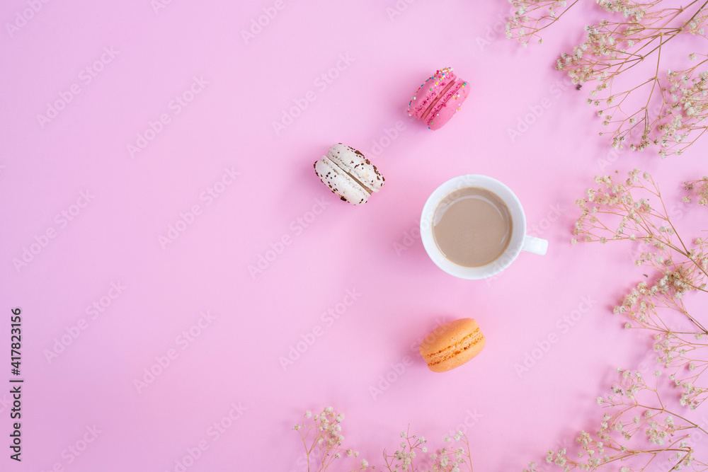 Cup of coffee and colorful macaron on pastel pink background top view. Cozy breakfast. Fashion flat lay. Sweet macaroons.