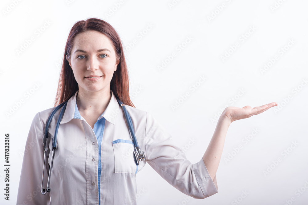 Portrait of a female doctor in a white uniform that shows a palm with copyspace in the studio on a white background Portrait of a female doctor in a white uniform that shows a palm with copyspace in the studio on a white background