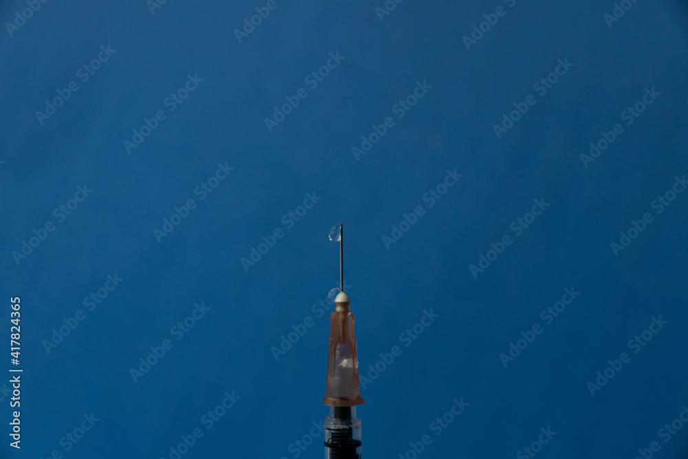Obraz premium The needle of a syringe with a vaccine close-up on a blue background