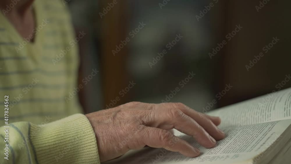 Man with wrinkled hand runs his index finger over page of wide opened old book. Man with wrinkled hand runs his index finger over page of wide opened old book.
