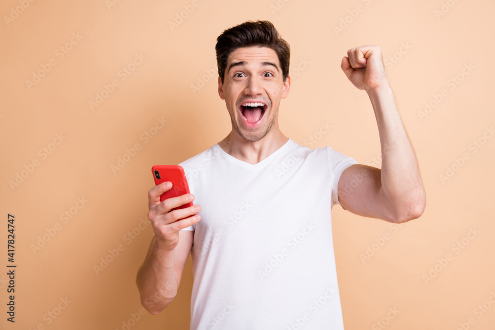 Photo of astonished person fist up open mouth shout yes celebrate triumph isolated on beige color background Photo of astonished person fist up open mouth shout yes celebrate triumph isolated on beige color background