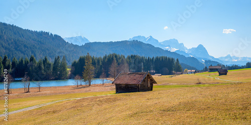 pasture with wooden hay hut, lake Geroldsee and Wetterstein mountains in spring