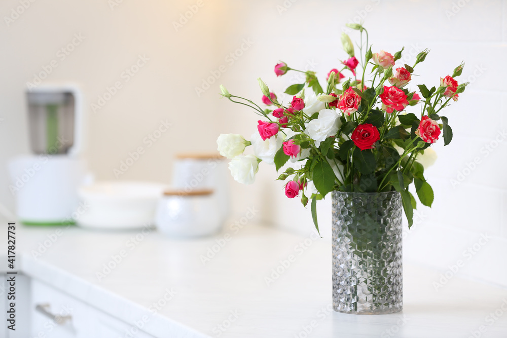 Vase with beautiful flowers on white countertop in kitchen, space for text