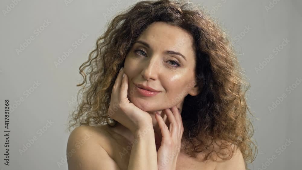 Charming middle-aged woman touches her face with her hands. Beautiful hair, fresh skin. Cosmetology, beauty and spa.