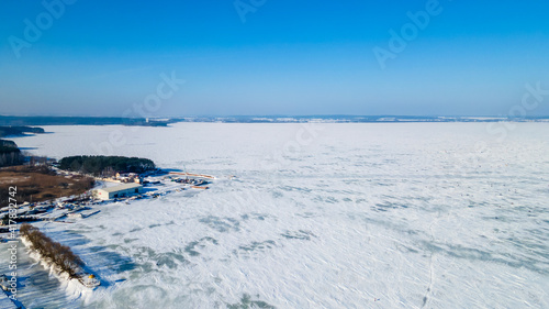 Fototapeta Naklejka Na Ścianę i Meble -  Aerial drone image of frozen lake and dam with snow. Ice from the drone view in winter. Beauty in nature concept.