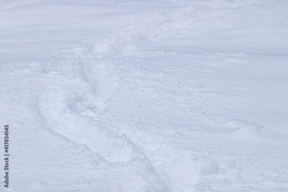 Footprints on beautiful shiny snow as background, closeup view