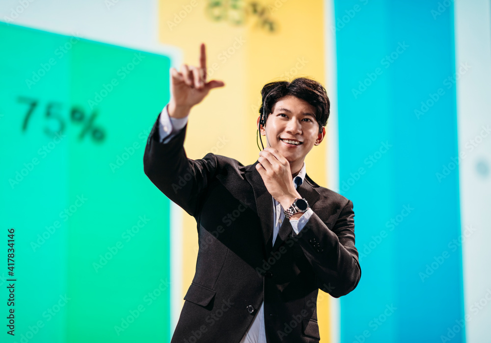 Male Asian Speaker Stands on Stage for Business Presentation