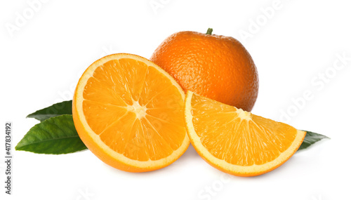 Cut and whole fresh ripe oranges with green leaves on white background