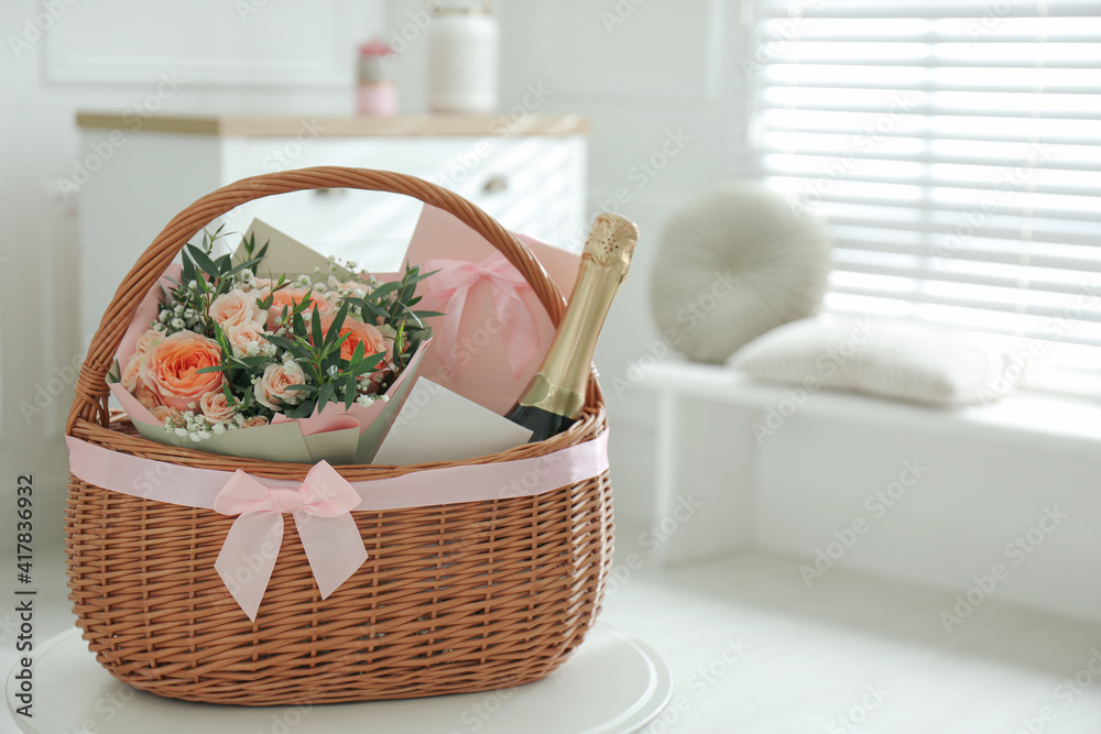 Wicker basket with gifts on table indoors. Space for text Wicker basket with gifts on table indoors. Space for text