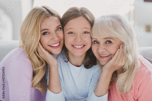 Photo of positive small girl woman and grandmother daughter hold hands cheeks smile indoors inside house