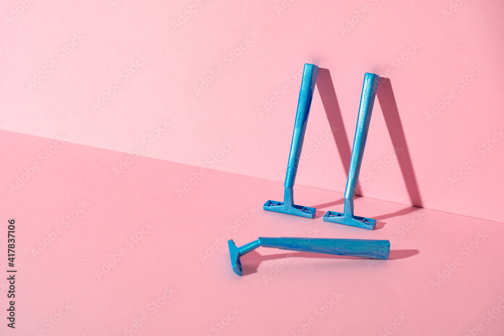 Blue disposable razors on pink paper background Blue disposable razors on pink paper background