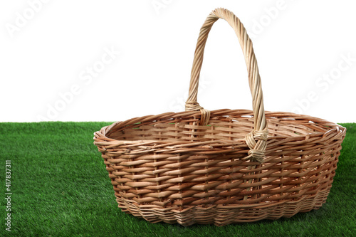 Empty wicker basket on green lawn against white background. Space for design. Easter item