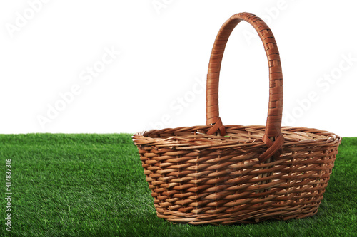 Empty wicker basket on green lawn against white background. Space for design. Easter item