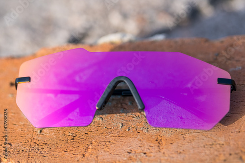 Futuristic sunglasses model rimless with big pink lens reflecting the sun in a summer day closeup. Selective focus . High quality photo photo