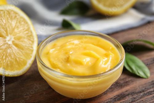 Delicious lemon curd in bowl on wooden table, closeup