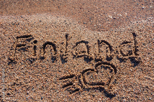 Small heart and word Finland handwritten on a sandy beach