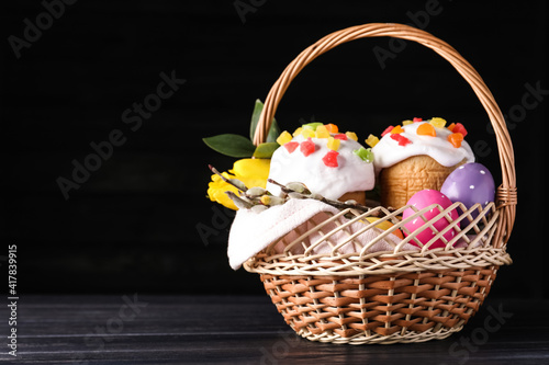 Traditional Easter cakes in wicker basket on dark background. Space for text