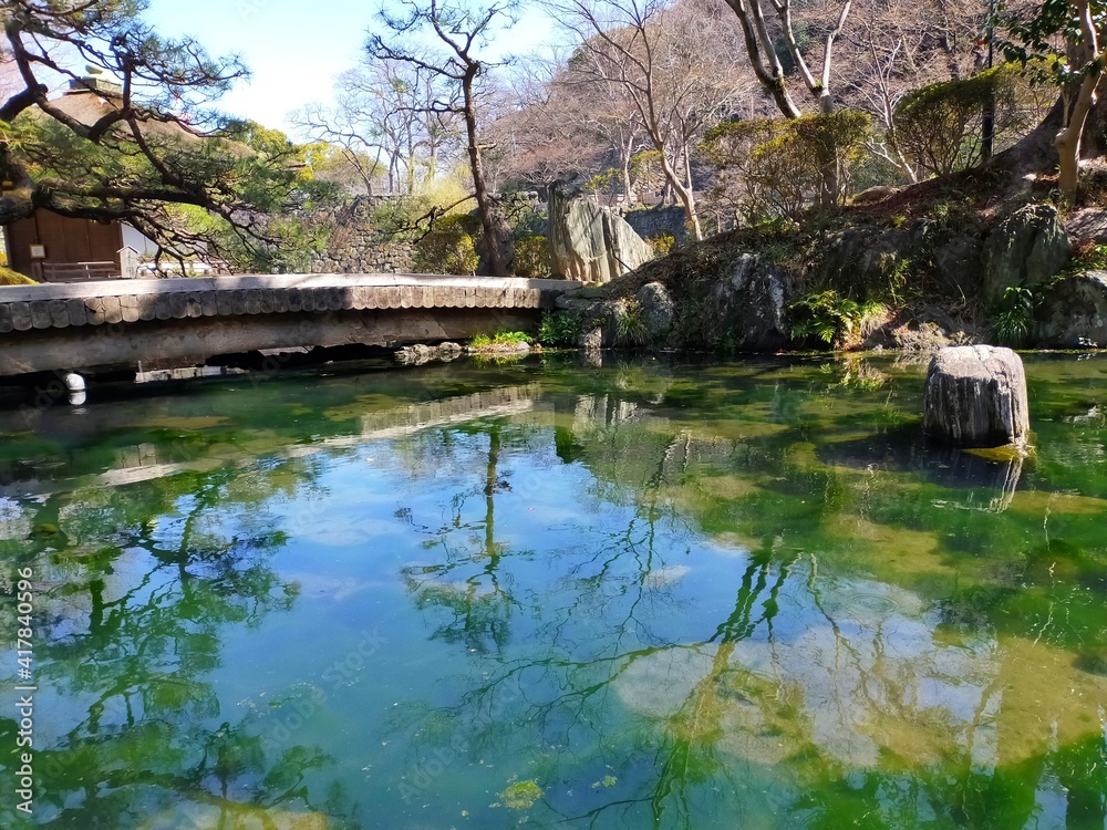 史跡和歌山城の日本庭園（紅葉谷庭園）の池の水に映り込んだ空と橋の冬の風景（コピースペースあり）