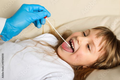 Swab for coronavirus. Doctor and patient child girl with Covid-19 lies in bed