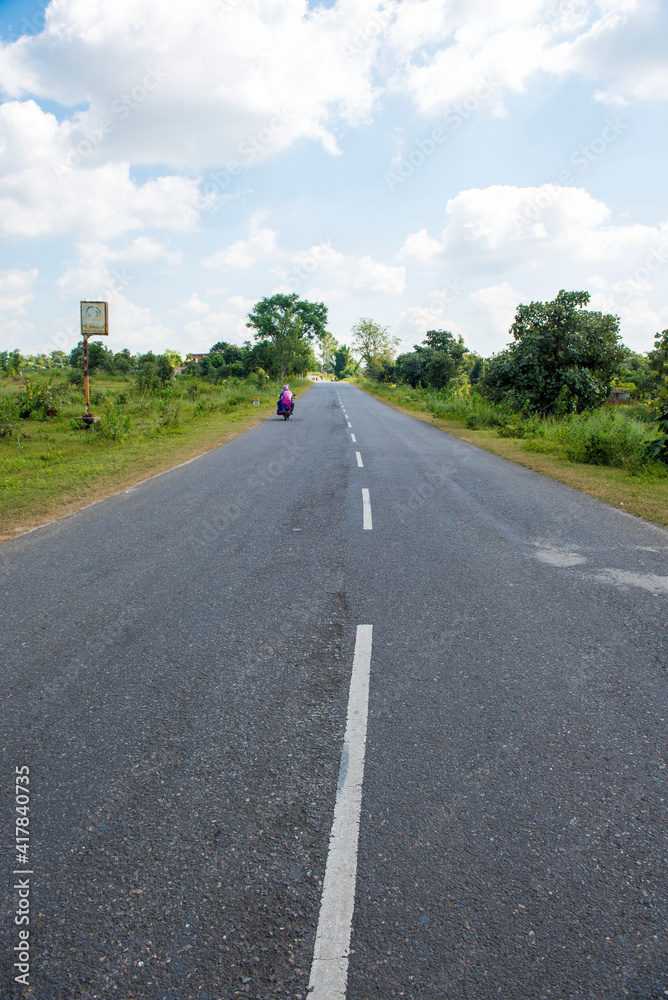 Fototapeta premium chirmiri / India 22 October 2017 A long straight road going thought the green field in Chirmiri Chhattisgarh India