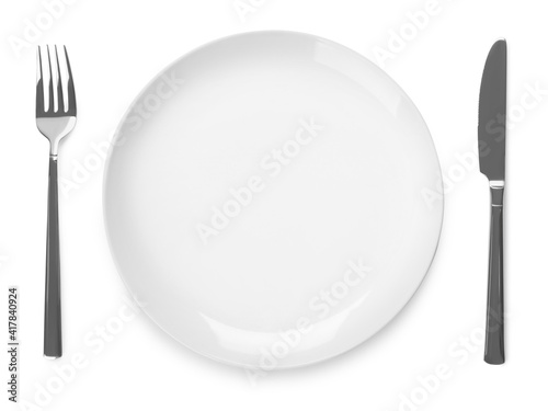 Plate and cutlery on white background, top view