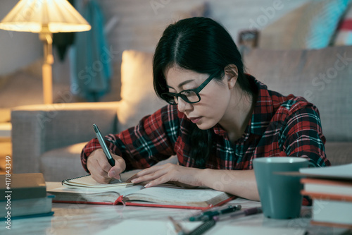 Foto female high school student is transcribing math formula from textbook with attentive look