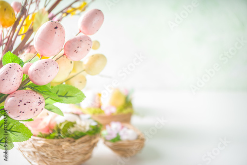 Easter greeting card background. Spring tree decor branches with colorful eggs  flowers and leaves on white background copy space for your text