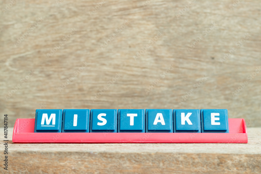 Obraz premium Tile alphabet letter with word mistake in red color rack on wood background