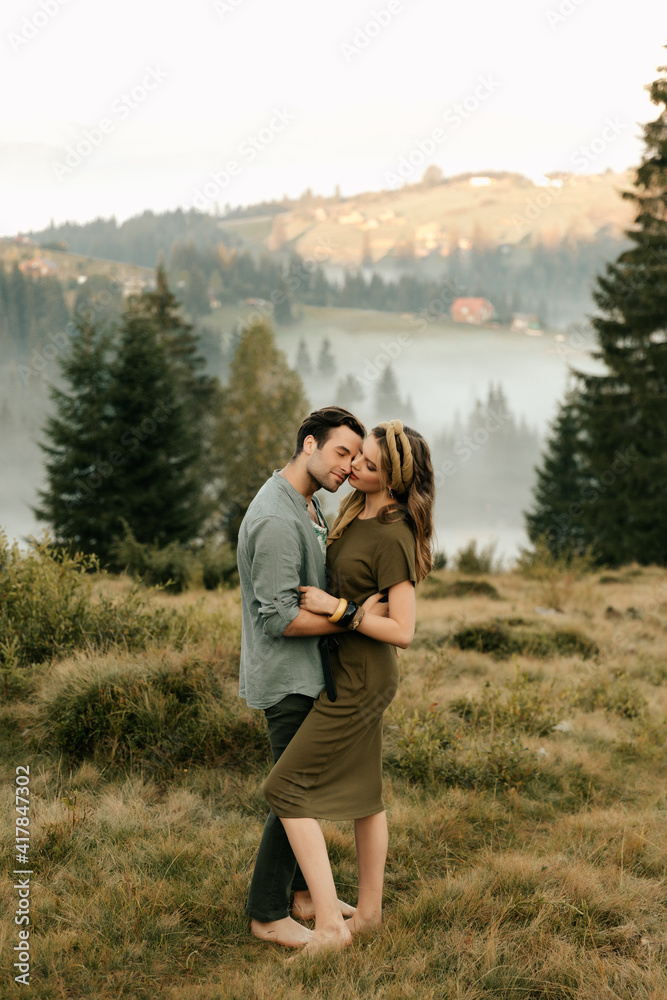 Happy young couple in love hugging and laughing in the mountains outdoors