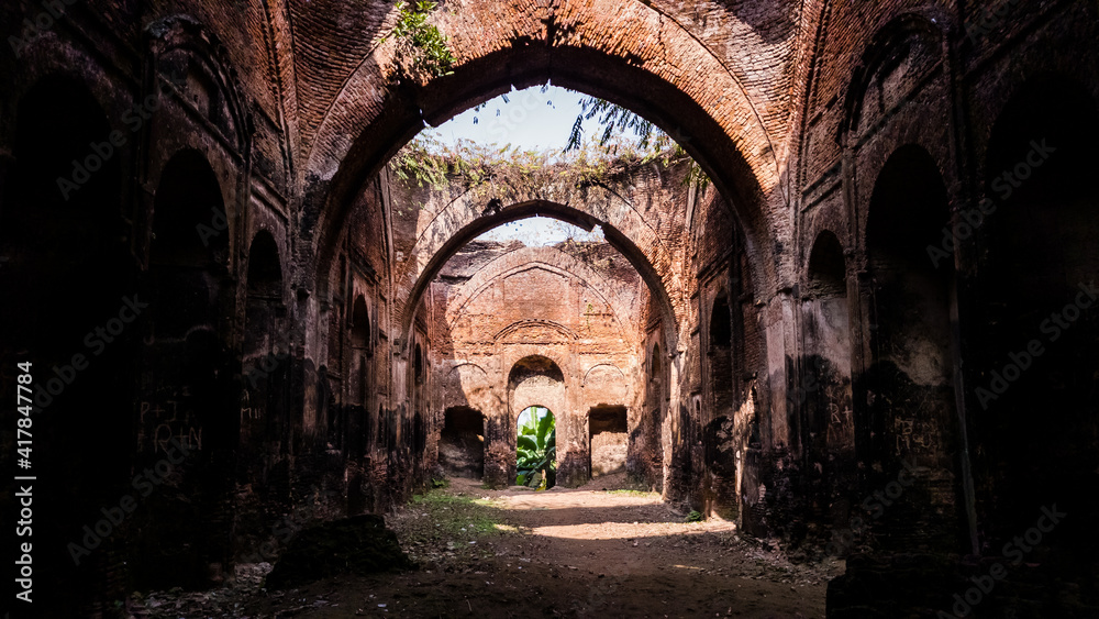 The arches in the overgrown ruins of an ancient dilapidated mosque in the town of Murshidabad in West Bengal, India.