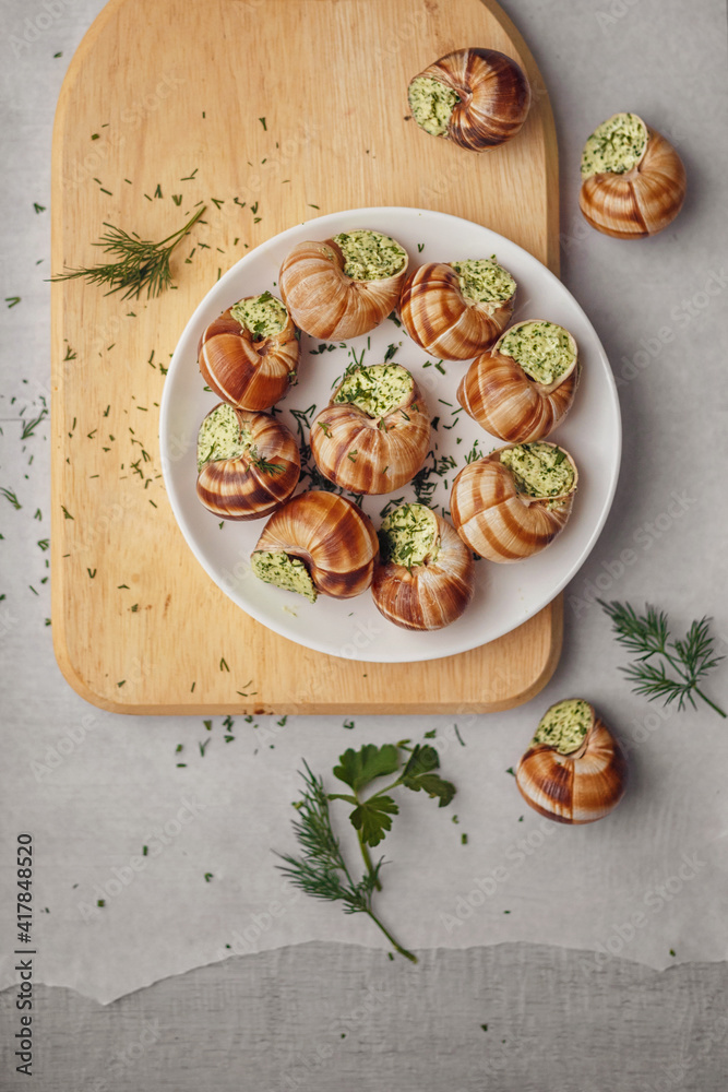 Burgundy escargots with green oil and parsley on a light board Burgundy escargots with green oil and parsley on a light board